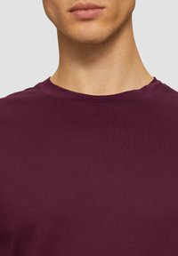 T-shirt à col rond à manches courtes en bourgogne profond, fabriqué en mélange de coton doux avec une texture lisse et un design minimaliste.