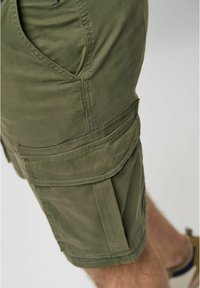 Olijfgroene cargo shorts van een katoenmengsel, met zijzakken, gestikte details en een ontspannen pasvorm. Duurzaam en veelzijdig ontwerp.