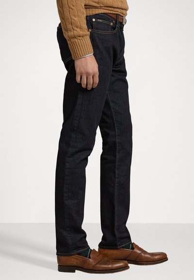 Mørkeblå denim jeans, slim fit, med kontrastsøm og femlommersdesign. Kombinert med brune lærloafers.