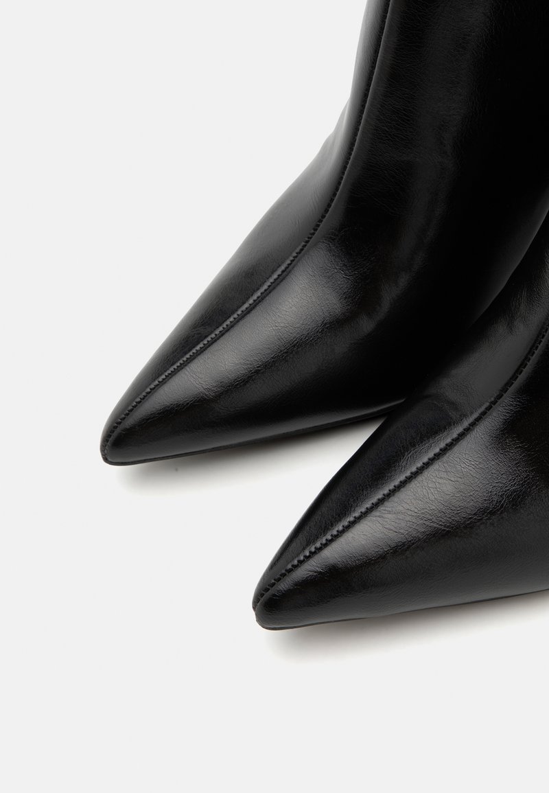 Stivaletti neri in pelle con punta affusolata, caratterizzati da una texture liscia, un design elegante e una sottile impuntura lungo i bordi.