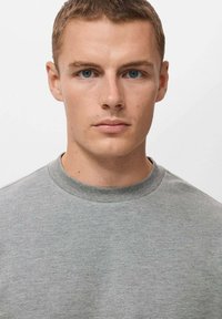 Sudadera de algodón gris con cuello redondo y mangas cortas. Textura suave y diseño minimalista. Sin patrones ni acentos visibles.