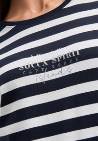 Striped navy and white cotton T-shirt with a crew neck. Features "Soccx Spirit Cape Verde" in silver print and a relaxed fit.