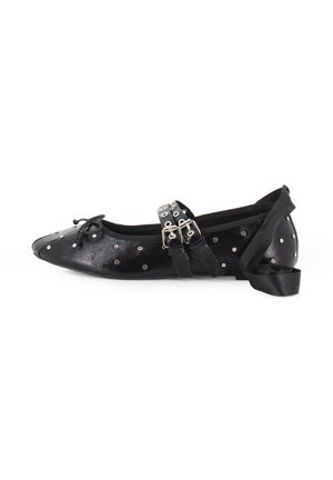 Bailarina de cuero negro con remaches plateados, punta afilada, detalle de lazo con cordones y correas de cuero dobles con hebillas metálicas.