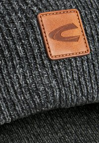 Donkergrijze gebreide beanie met een textuurpatroon en een rechthoekige faux leren patch met een geperst logo, gestikt in bruin.