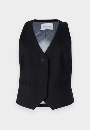 Gilet senza maniche nero con scollatura a V, chiusura con un solo bottone e due tasche frontali. Fodera grigia liscia con motivo a pois.