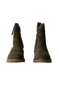 Stivaletti in suede verde oliva con superficie testurizzata, dotati di chiusura con zip, punta rotonda e suola in gomma marrone con motivi antiscivolo.