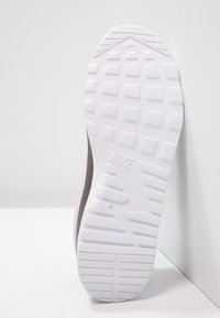 Suela de zapatilla Nike con material de goma blanca, patrón texturizado para agarre, presentando un logo sutil y una forma redondeada y contorneada.