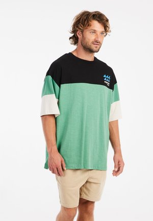 Kortærmet t-shirt i sort, grøn og cremefarvet, med et vandret farveblokkede design og et logo på brystet.