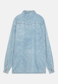 Camicia in denim azzurro chiaro con maniche lunghe, colletto a punta e polsini con bottoni. Presenta una texture sbiadita e cuciture a doppio punto.