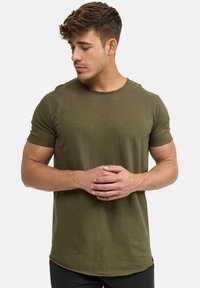 T-shirt verde oliva a maniche corte in una vestibilità rilassata, con scollatura rotonda e tessuto morbido, completato da un orlo curvo.