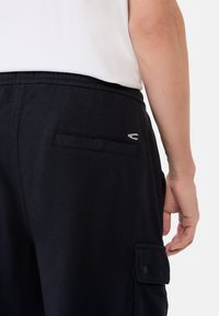 Marine cargobroek gemaakt van textuurstof. Heeft een knoopzak aan de achterkant en een geborduurd logo op de tailleband. Elastische taille.