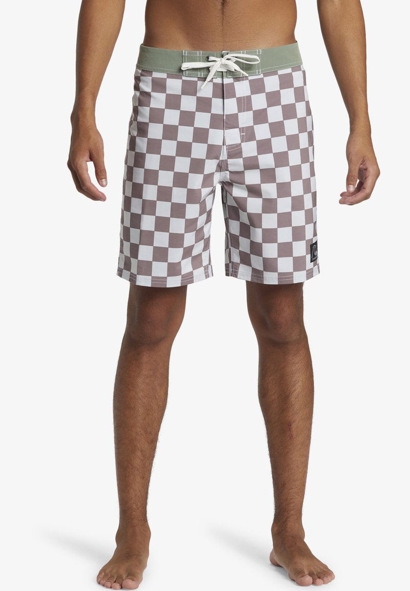 Checkered swim shorts in brown and white. Features a green waistband and drawstring, with a patch logo on the left side. Made of lightweight material.