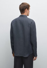Dark gray shirt with long sleeves and a relaxed fit, featuring a subtle texture and a classic collar; back view shows a rounded hem.