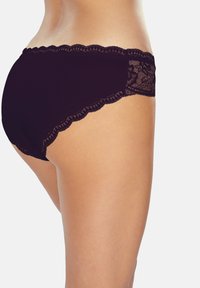 Schwarze Unterwäsche mit einem gewellten Spitzenrand am Bund und einem transparenten Spitzenpaneel an der Seite, das einen glatten, weichen Stoff betont.