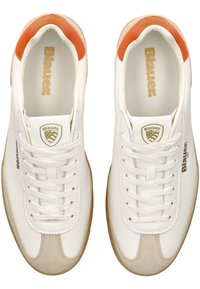 Bílé tenisky s koženými a semišovými panely, s tan gumovou podrážkou, oranžovým akcentem na patě a výrazným logem značky.