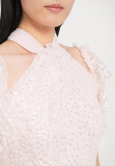 Rózsaszín ruhadarab texturált anyaggal, ezüst flitterekkel, fodros vállrészletekkel és puha, széles halter nyakpánttal.