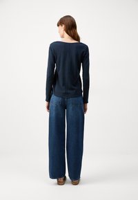 Navy long-sleeve top with a scoop neckline, paired with wide-leg blue jeans. Simple design, soft texture, casual fit.