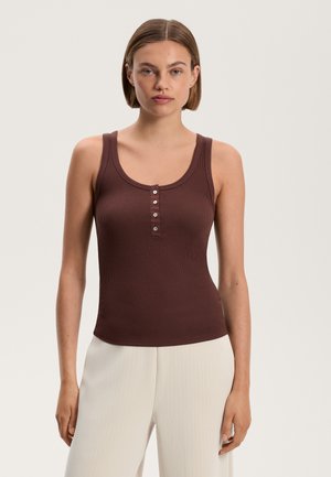 Burgundy ribbed tank top with a scoop neckline, featuring a five-button placket. Worn with light-colored, wide-legged trousers.