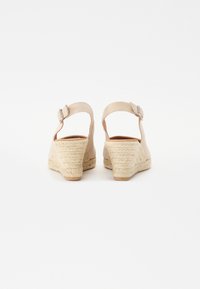 Beesidised kreemikad sandaalid, mis on valmistatud kangast ja millel on espadrille-stiilis jute konts. Omab pahkluu rihma metallist pandlaga.