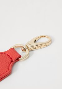Röd lädernyckelringsrem med strukturerad finish, utrustad med en klämma i guldton och graverad "VALENTINO"-detalj.