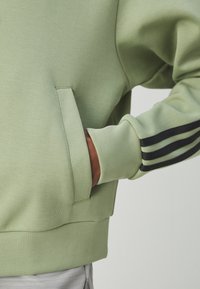 adidas Sportswear FUTURE ICONS THREE STRIPES FULL ZIP - Camisola com fecho - tent green