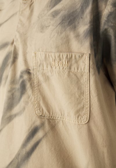 Beige skjorte med tie-dye design, der har en påsyet lomme og broderet "MSGM" logo. Glat tekstur med et let krøllet udseende.