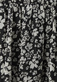 Musta kangas valkoisilla kukkakuoseilla, jossa on ristikkäinen tekstuuri ja joustava vyötärö. Kukat vaihtelevat koossa ja muodossa.