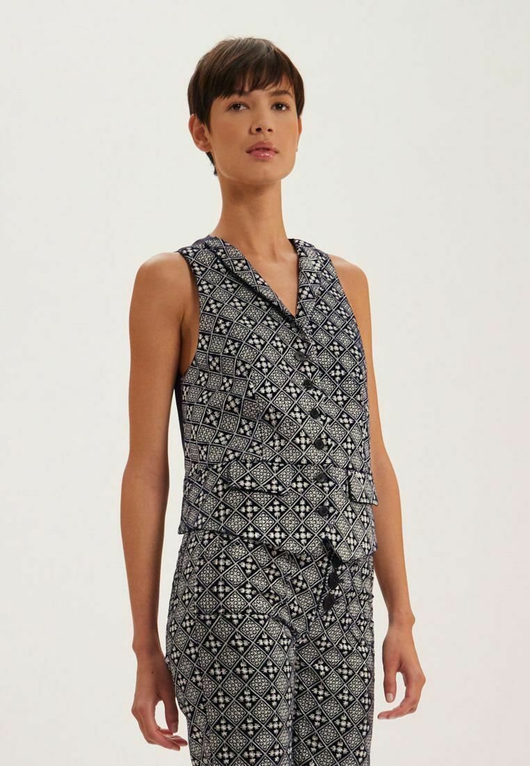 Haut sans manches avec un motif géométrique bleu marine et blanc, avec un décolleté en V et un design superposé. Le tissu a une texture lisse et un léger éclat.