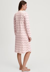 Chemise da notte a maniche lunghe in tessuto rosa chiaro con una stampa floreale ripetuta, texture a coste e orlo arrotondato.