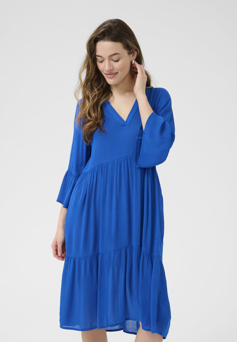 Abito blu fluido con scollo a V, maniche a campana a tre quarti, design a strati e tessuto leggero e testurizzato.