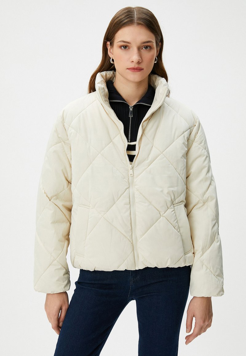 Gepolsterte weiße Pufferjacke mit hohem Kragen, Reißverschluss und zwei Seitentaschen. Bietet eine kastige Passform und eine weiche, glatte Textur.
