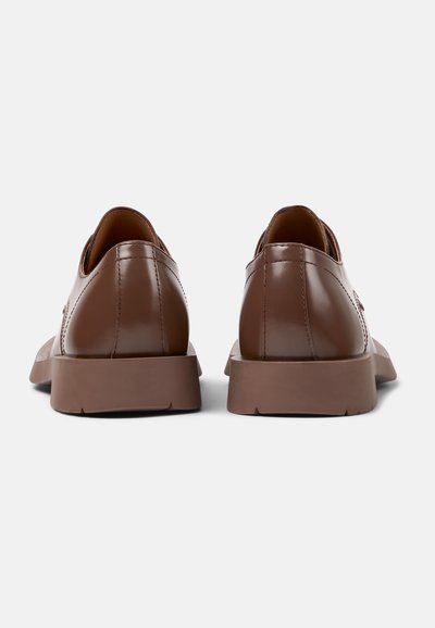 Scarpe in pelle marrone con finitura liscia, punta arrotondata e suole in gomma modellata. Presentano cuciture minime e un design elegante e moderno.