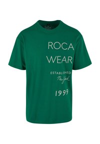 Grøn bomulds t-shirt med rund hals; har "ROCA WEAR" i store bogstaver og mindre tekst der siger "ETABLERT New York 1999."