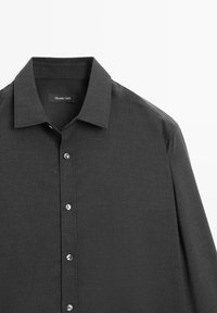 Donkergrijze lange mouw shirt met een gestructureerde kraag, textuurstof en zilveren knopen aan de voorkant. Merkentiket zichtbaar binnen in de kraag.