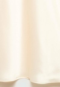 Saténová tkanina v krémové barvě, hladký povrch s jemným leskem. Zaoblený lem s viditelnými stehmi. Žádné vzory ani ozdoby.