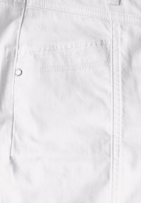 Tela de algodón blanca con una textura suave, que presenta un bolsillo trasero con costura y un botón plateado redondo.