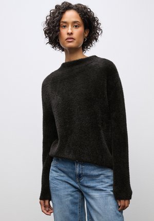 Zwarte, fuzzy trui met een hoge halslijn en lange mouwen, gecombineerd met lichtblauwe denim jeans. Zachte textuur, ontspannen pasvorm.