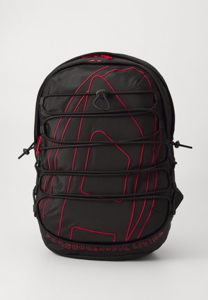 Schwarzer Nylon-Rucksack mit roten Akzenten in der Naht, einer strukturierten Oberfläche und verstellbaren Trägern. Gestickter Text am unteren Rand lautet: "FÜR EIN ERFOLGREICHES LEBEN."