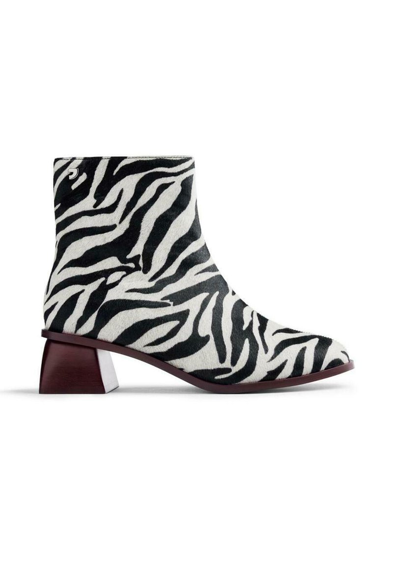 Botín tobillo con estampado de cebra que presenta un material sintético suave, un tacón bloque afilado y una combinación de colores en blanco y negro, con una punta ligeramente puntiaguda.