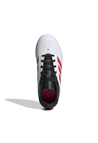 Zapatilla deportiva blanca con acentos negros y rayas diagonales rojas. Cuenta con una parte superior texturizada y cordones redondos, con un logotipo en el talón.