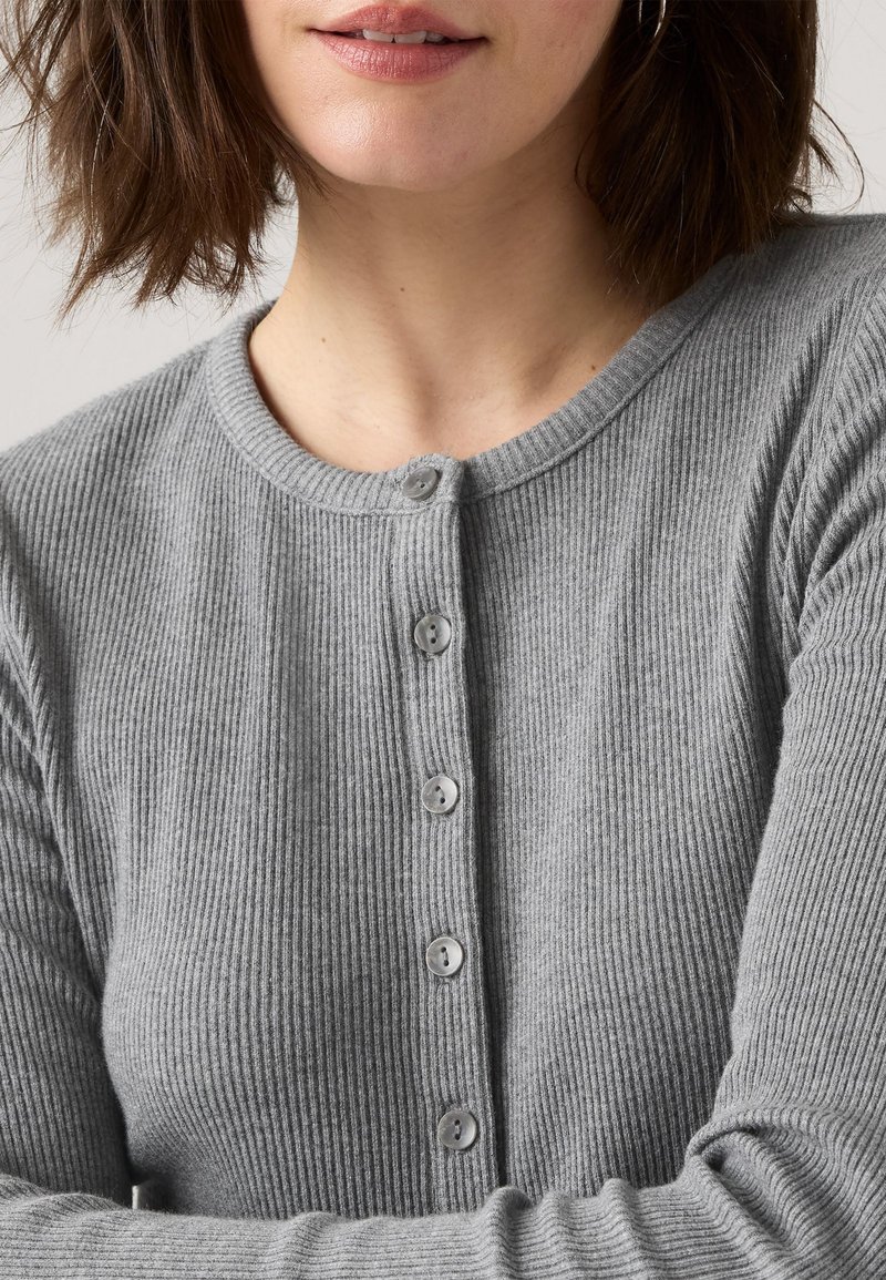 Graue gerippte Strickjacke mit rundem Ausschnitt und durchgehender Knopfleiste mit fünf grauen Knöpfen. Weicher, strukturierter Stoff.