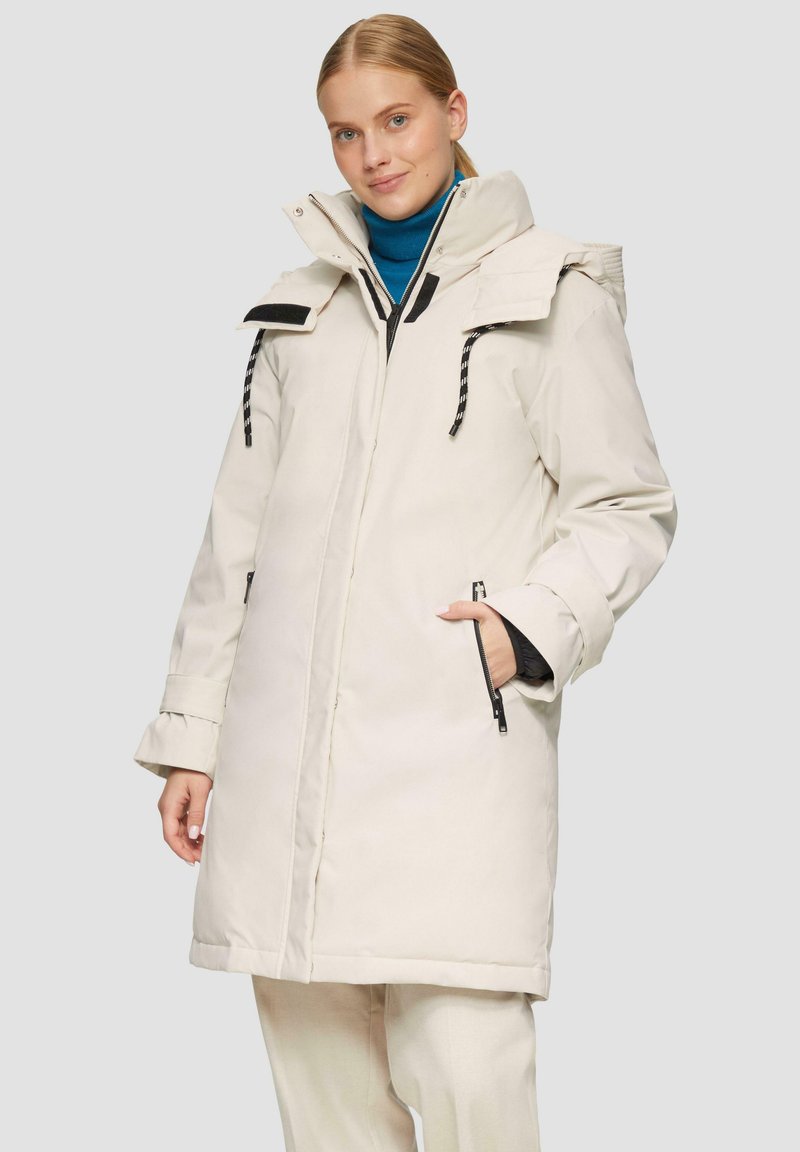 Witte geïsoleerde parka met een hoge kraag, met rits afgesloten zakken, verstelbare trekkoord en contrasterende zwarte hardware en accenten.