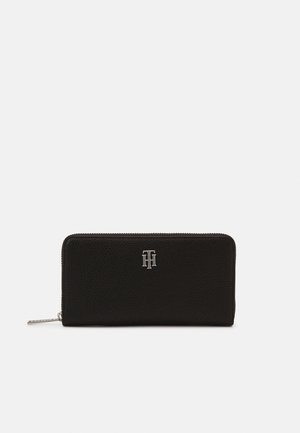 Portefeuille en cuir noir avec fermeture éclair tout autour et petit logo argenté Tommy Hilfiger centré sur le devant.