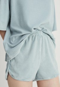 Lichtblauwe fleece lounge set bestaande uit een losse top met korte mouwen en shorts met elastische tailleband en zijsplitten voor comfort en bewegingsvrijheid.