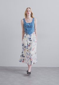 Jeansbuste med en tætsiddende form, parret med en flydende, blomsterpræget nederdel i hvid, med blå og røde detaljer.