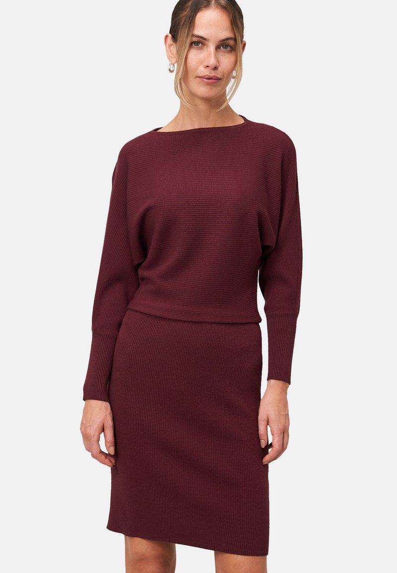 Robe en tricot bourgogne avec une texture côtelée, présentant une encolure bateau, des manches longues et une silhouette de jupe ajustée.
