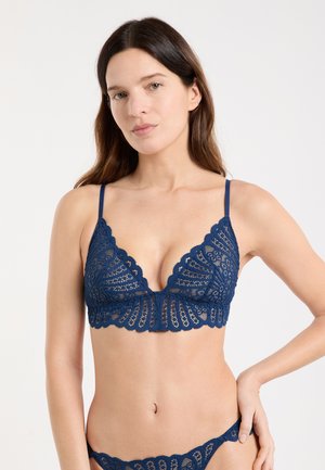 Bralette de encaje azul marino con bordes con volantes, copas triangulares y tirantes delgados ajustables. Patrones intrincados realzan el aspecto texturizado.