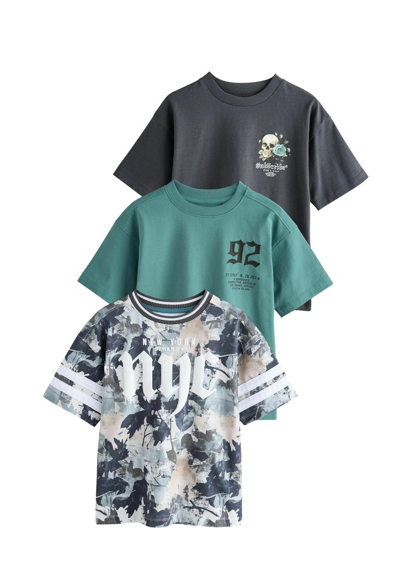 Tři trička vystavená: nahoře tmavě šedé tričko s grafikou lebky, uprostřed zelené tričko s velkým nápisem '92', dole tričko s barevným maskáčovým vzorem a textem 'nyc'.