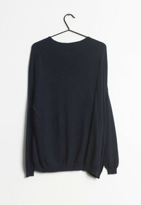 Mörk marinblå tröja hängande på en svart krok. Har långa ärmar, en rund halsringning och en lös passform med en strukturvävd textil.