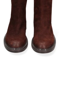 Bruine suede enkellaarzen met een ronde neus, voorzien van studdetail rond de zool en een platte, gestructureerde buitenafwerking.